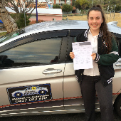 Student standing next to driving vehile with her assessmnt pass in her hand