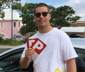 Young man standing by our driving school vehicle showing both P plates afetr passing driving assessment