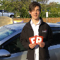 Young male holding up P plates after passing driving test